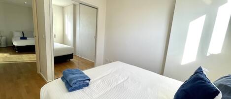 A bedroom with a bed, a blue towel, a dark blue pillow, and a wardrobe.