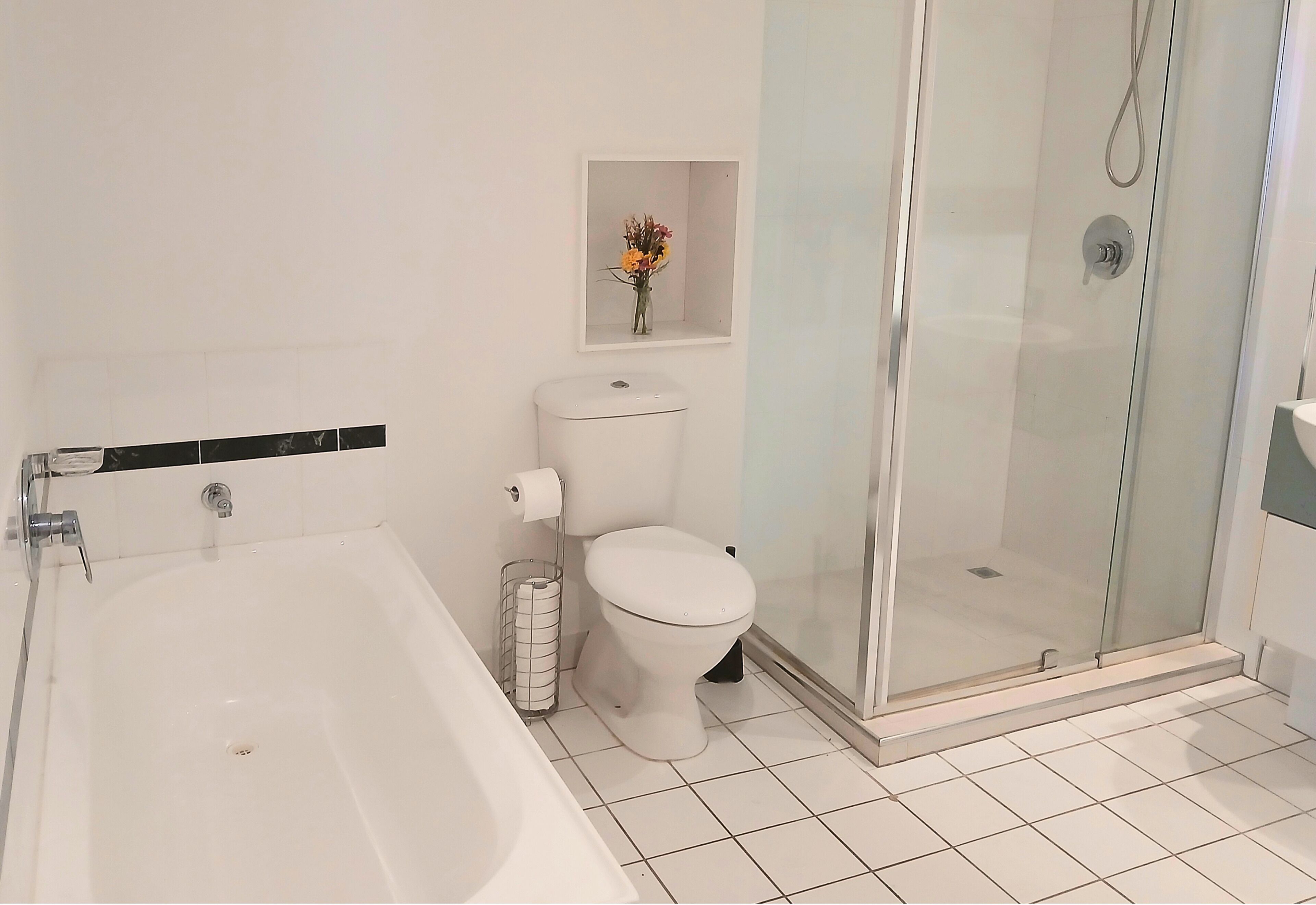 A modern bathroom with a bathtub, toilet, and glass-enclosed shower.