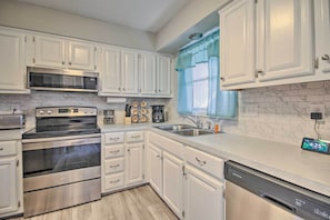 A modern kitchen with white cabinets, stainless steel appliances, and a digital clock displaying 4:25.