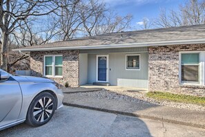 A single-story brick house with a front porch, a blue door, and a driveway.