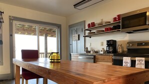 Une cuisine moderne avec une table en bois, une bouilloire jaune et des tasses rouges disposées sur des étagères.