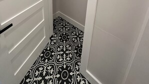 Un vestidor amplio con piso estampado, una barra para colgar ropa y una puerta de paneles horizontales.