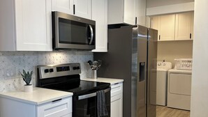 Una cocina moderna con armarios blancos, electrodomésticos de acero inoxidable y un salpicadero de azulejos.