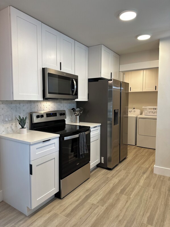 A modern kitchen with white cabinets, stainless steel appliances, and a tiled backsplash.