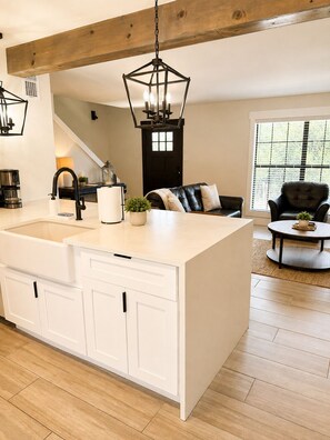 Una cocina moderna con una isla central, armarios blancos y una lámpara colgante.