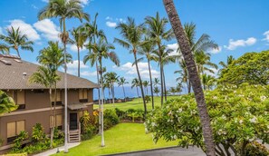 A hotel with a brown exterior, a covered outdoor area, and a view of the ocean. - Aloha Condos, Kanaloa at Kona, Condo 1404, Ocean View, AC (Kailua Kona)
