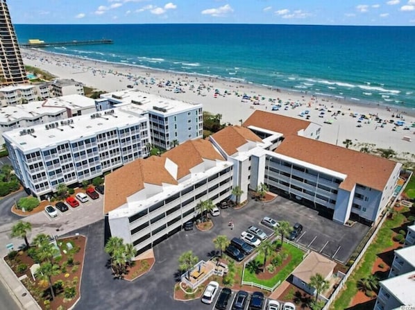 An aerial view of a coastal area with a beach, a parking lot, and several buildings. - CLEAN! On the Beach! Best Views! FREE Beach Gear! (Myrtle Beach)