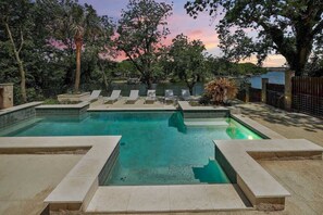 A rectangular pool with multiple lounge chairs and a stone border.