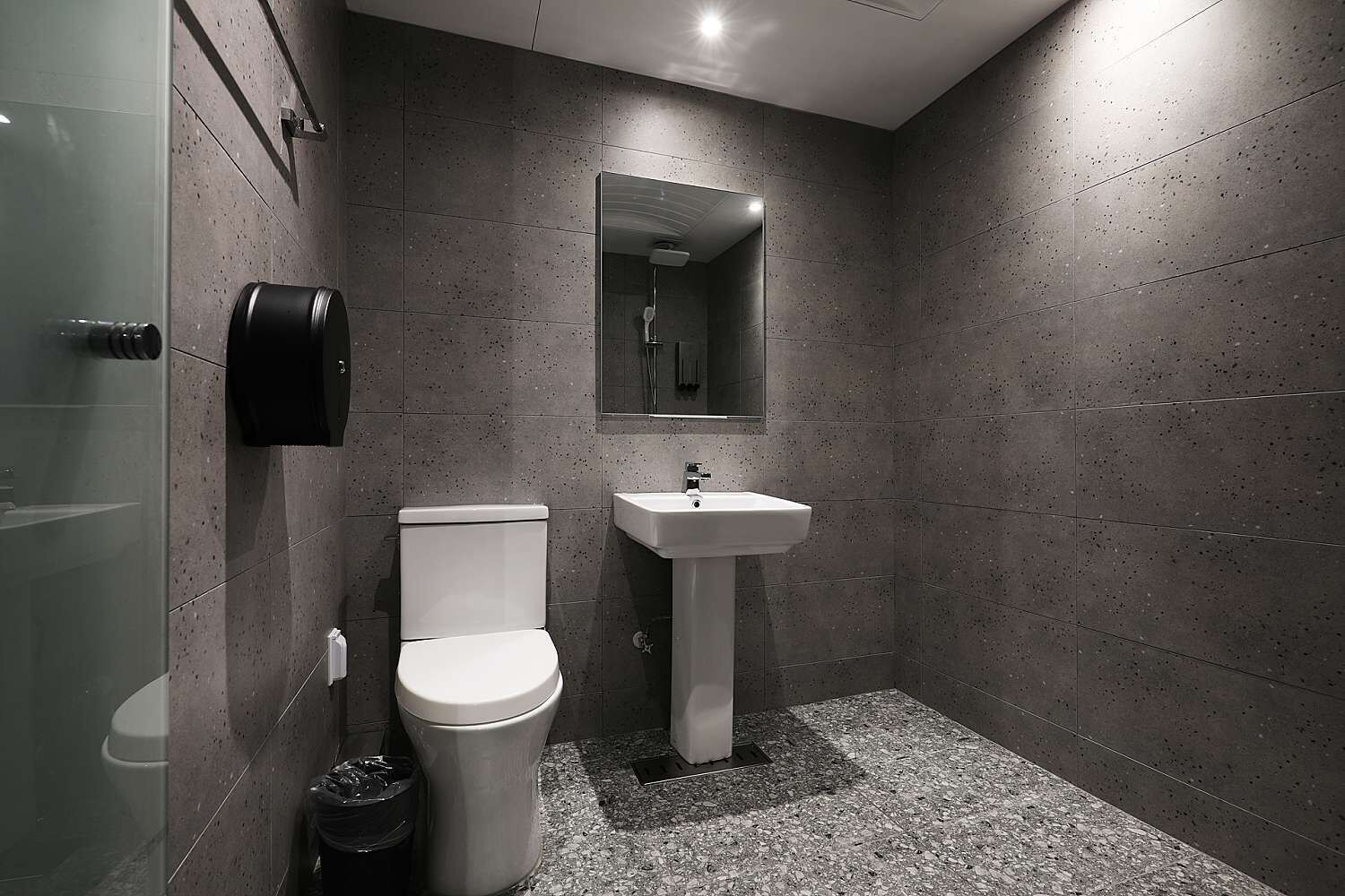 Une salle de bain moderne équipée de toilettes, d’un lavabo et d’une douche à parois de verre.
