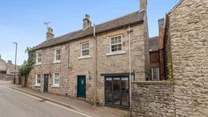 A stone building with a green door, a window with a shutter, and a small porch area. - Cottage in the heart of the Peak District (Matlock)