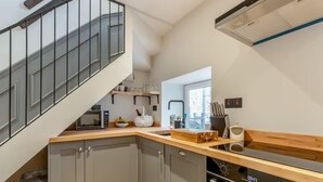 A modern kitchen with grey cabinets, a wooden countertop, a microwave, a sink, and an oven. - Cottage in the heart of the Peak District (Matlock)