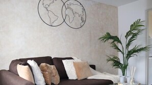 Ein modernes Wohnzimmer mit einem braunen Ecksofa, einem Glastisch und einer großen Topfpflanze.