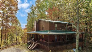 Une cabane avec une véranda, un escalier et une allée bordée d’une clôture.