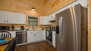 Une cuisine moderne dotée d’appareils électroménagers en acier inoxydable, de meubles blancs et d’un plancher en bois.