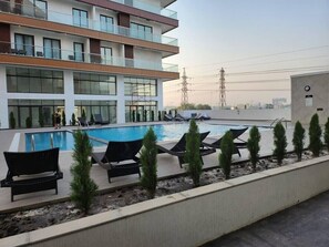 Ein Poolbereich auf dem Dach mit Liegestühlen und einem modernen Gebäude im Hintergrund.