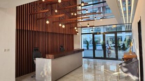 Un espace d'accueil moderne avec un mur à lattes en bois, un comptoir d'accueil et un coin salon comprenant un canapé et un fauteuil.