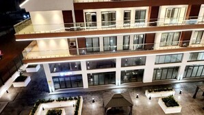 Un hôtel à plusieurs étages doté d’une cour intérieure, d’un espace extérieur aménagé pour s’asseoir et d’un pavillon couvert.