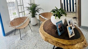 A room with a round wooden table, two wicker chairs, a potted plant, and a framed picture. - Hermosa Y Divertida Casa, Cerca A LA Playa Y AL Centro Histórico (Santa Marta)