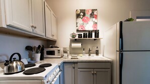 Una cocina con armarios blancos, estufa, microondas y refrigerador.