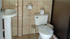 Un baño pequeño con lavamanos, inodoro y una toalla colgada en la pared.