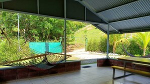 Un espacio exterior cubierto con una hamaca, bancos y vistas a un exuberante jardín.