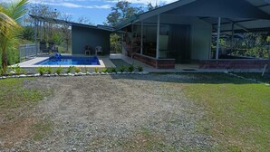 Una casa moderna con piscina, terraza techada y vistas del paisaje circundante.