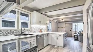 A modern kitchen with white cabinetry, a large island, and a view to the living area. - Tahoe Time Cabin w/King Bed, Modern Tahoe Cabin w/ King Bed Suite & Level 1 EV Charging (Incline Village)