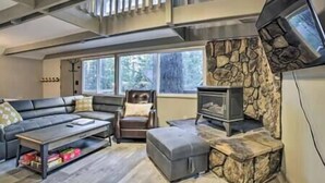 A modern living room with a stone fireplace, a sofa, a coffee table, and a television mounted on the wall. - Tahoe Time Cabin w/King Bed, Modern Tahoe Cabin w/ King Bed Suite & Level 1 EV Charging (Incline Village)