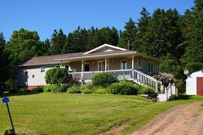 A single-story house with a front porch, a small front yard, and a dirt path leading to the front door. - Cozy private cottage with picturesque scenery (New Glasgow)