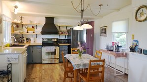 A kitchen with wooden cabinets, a stove, a sink, and a dining table with chairs. - Cozy private cottage with picturesque scenery (New Glasgow)