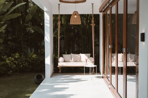 Et moderne interiør med en hvid sofa, et lille rundt bord og en hængende vævet lampe.