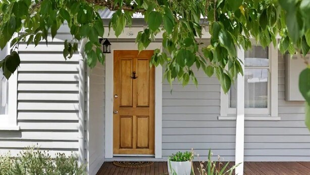A wooden front door with a white porch and a small white planter with green plants. - North Edge Cottage ~ Free Parking, City, Warm (Launceston)