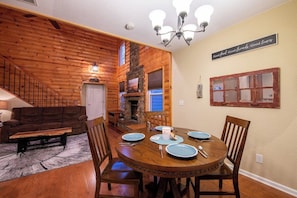 Uma sala de jantar com mesa de madeira, cadeiras e lareira.