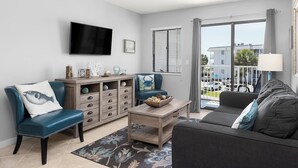 A modern living room with a flat-screen TV, a sofa, a chair, and a coffee table. - Beachfront Getaway at Gulf Shores Plantation! (Gulf Shores)