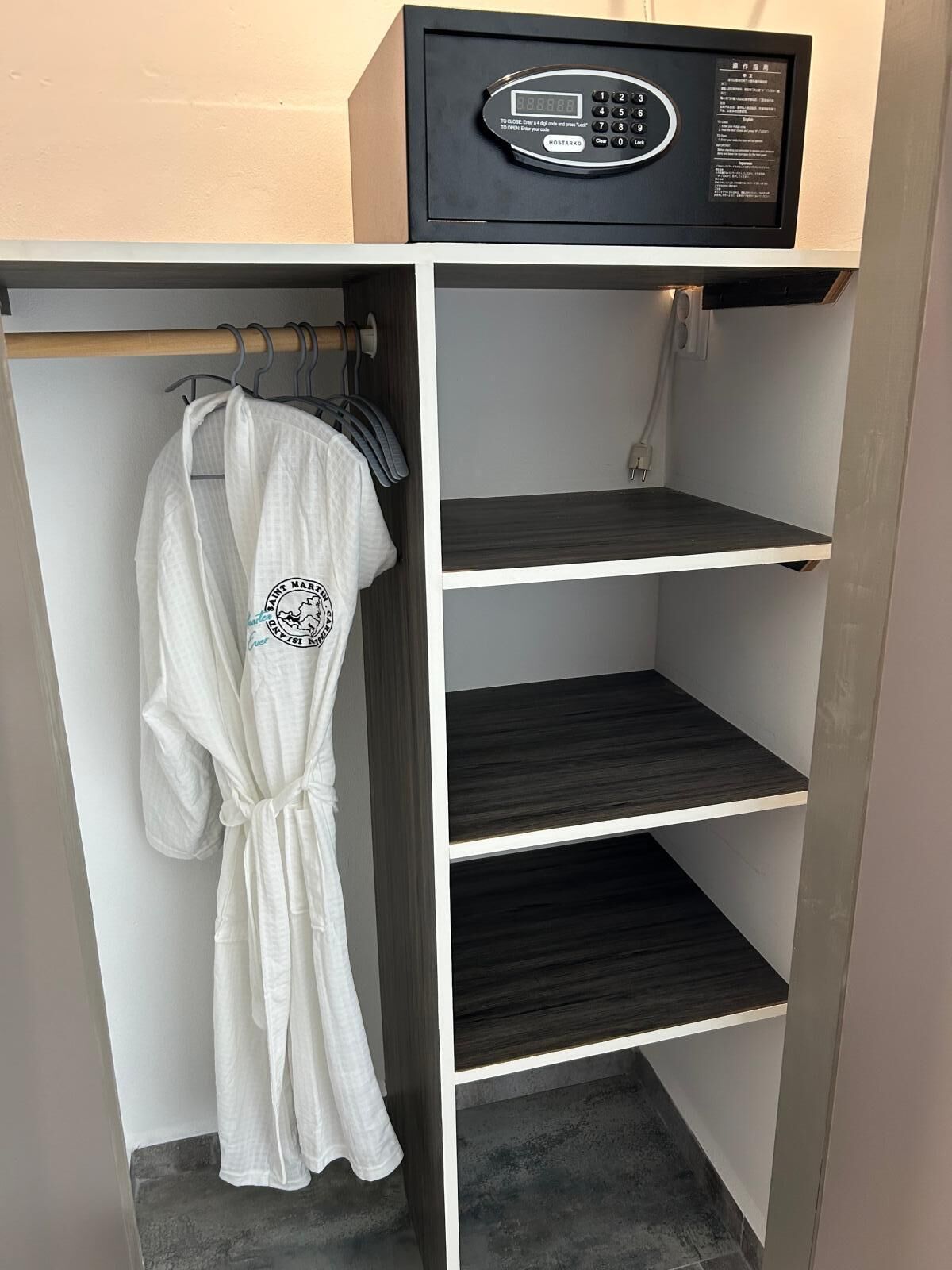 A hotel room with a minibar, a robe hanging on a rack, and a grey tiled floor.