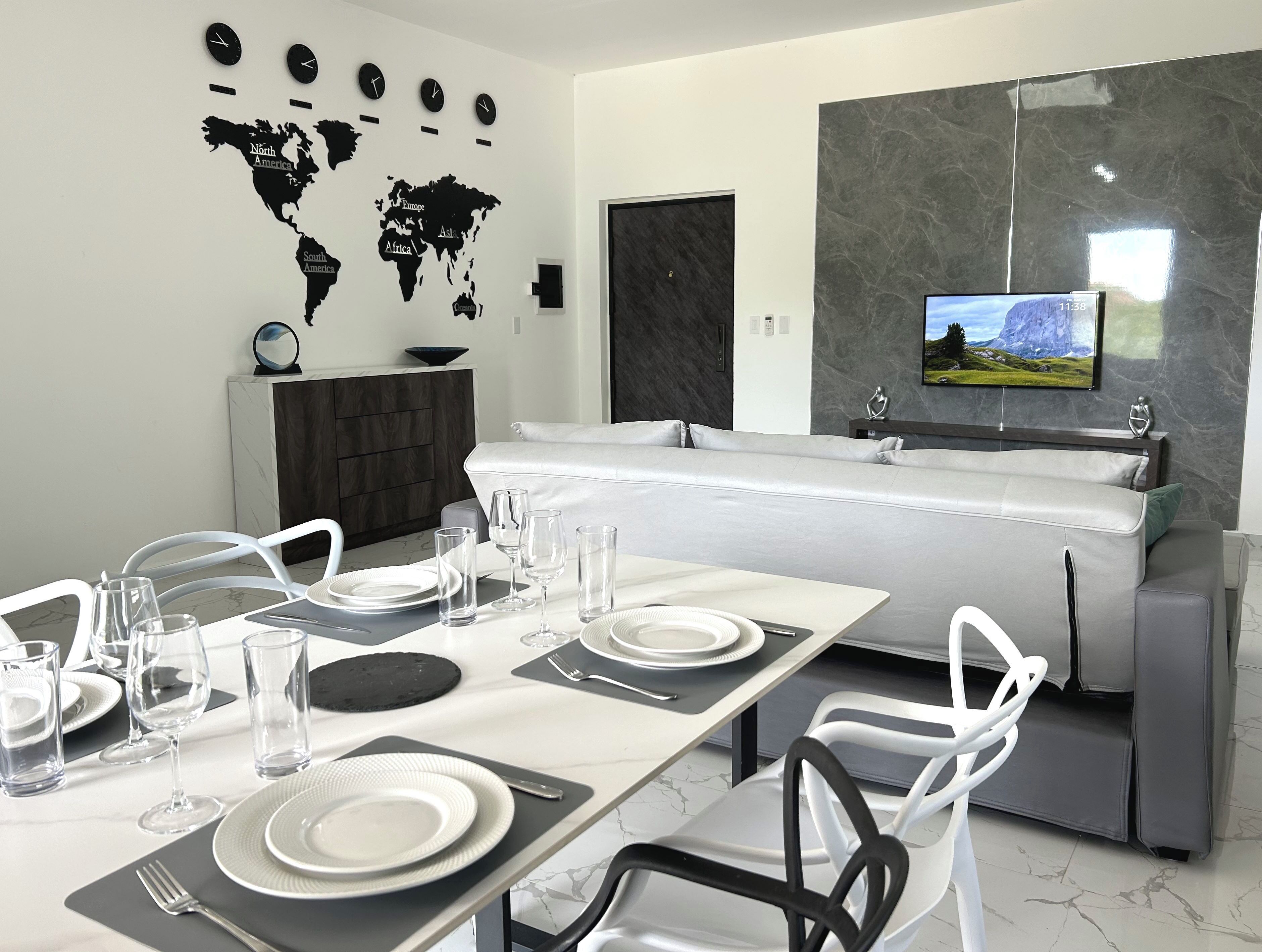 Un espace repas moderne agrémenté d’une carte du monde au mur, d’un téléviseur à écran plat et d’un canapé.
