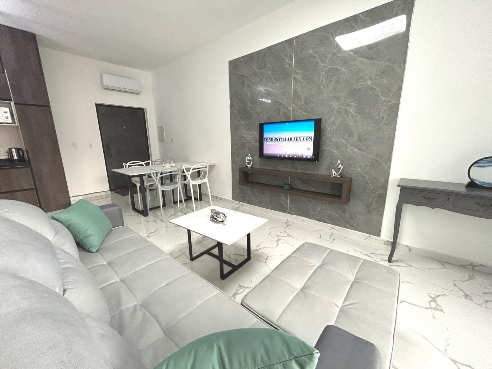 Una sala de estar moderna con un sofá, una mesa de centro y un televisor montado en la pared.