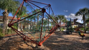 Une aire de jeux avec une structure d’escalade et un toboggan.