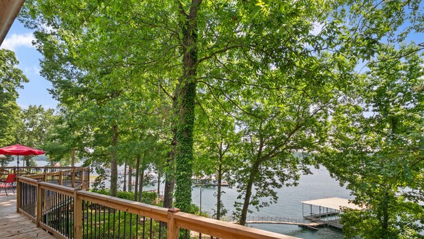 A wooden deck with a railing overlooking a lake, surrounded by lush greenery. - Duskin Point Retreat - near Duskin Point Marina (Jasper)