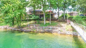 A riverside view with a stone bridge, a wooden deck, and a building with a balcony. - Duskin Point Retreat - near Duskin Point Marina (Jasper)