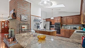 A spacious kitchen with a brick fireplace, granite countertops, and modern appliances. - Duskin Point Retreat - near Duskin Point Marina (Jasper)