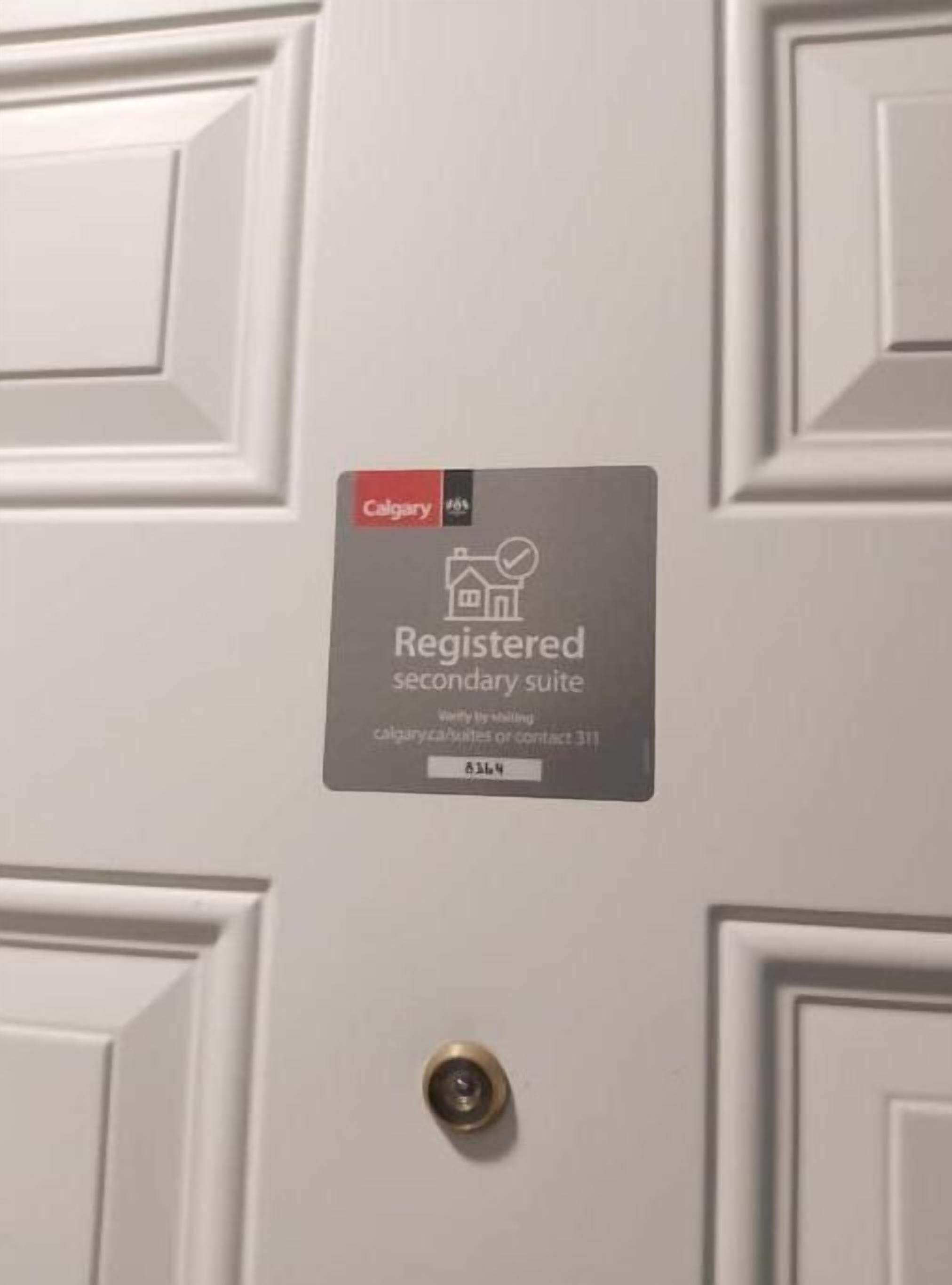 Puerta con placa que indica una segunda vivienda registrada en Calgary.