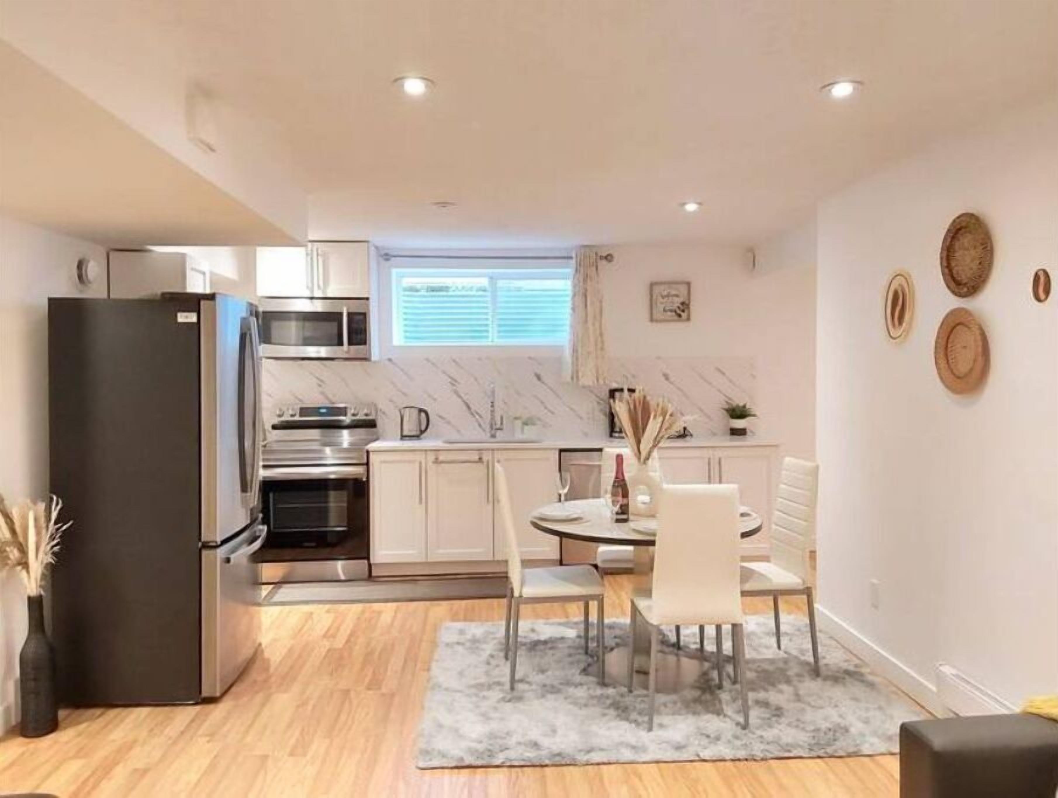 A modern kitchen with a refrigerator, stove, and microwave. There is a dining area with a table and chairs.