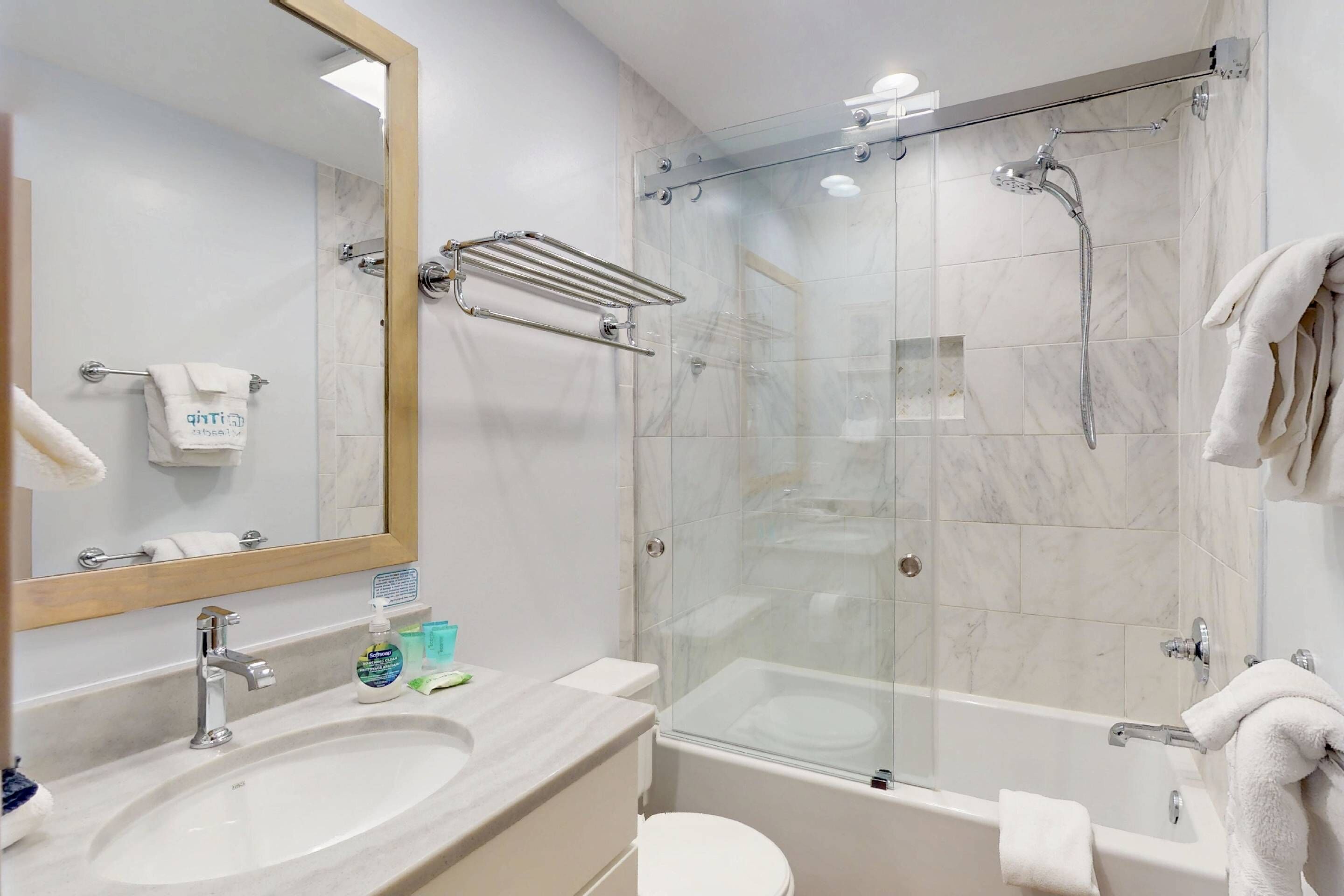A modern bathroom with a glass-enclosed shower, a sink with a mirror, and a toilet.