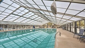 Una piscina interior con techo de vidrio y estructura metálica.