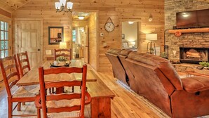 Un interior de madera con una mesa de comedor, sillas, un sofá y una chimenea.