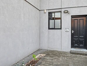 A building exterior with a black door, a window, and a small garden area.