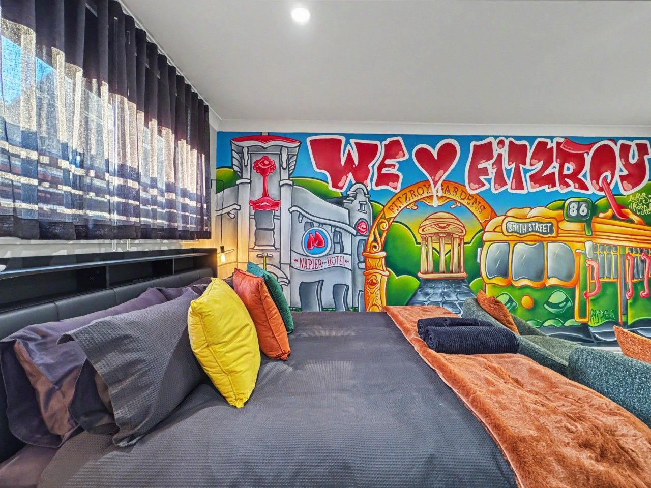 A room with a mural, a sofa, and a bed.