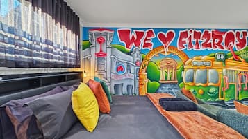 A room with a mural, a sofa, and a bed.