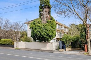 A two-story residential building with a large tree in front.